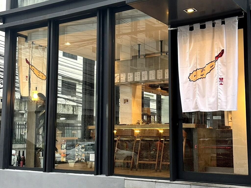 海老の天ぷらを染め抜いたのれんが掛かる、博多天ぷら ながおか バンコク プロンポン店の外観